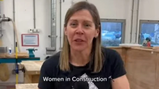 A female lecturer in a black Adidas t-shirt speaking in a joinery workshop at Glasgow Kelvin College, introducing the 'Women in Construction' course, with workbenches and tools visible in the background A female lecturer in a black Adidas t-shirt speaking in a joinery workshop at Glasgow Kelvin College, introducing the 'Women in Construction' course, with workbenches and tools visible in the background
